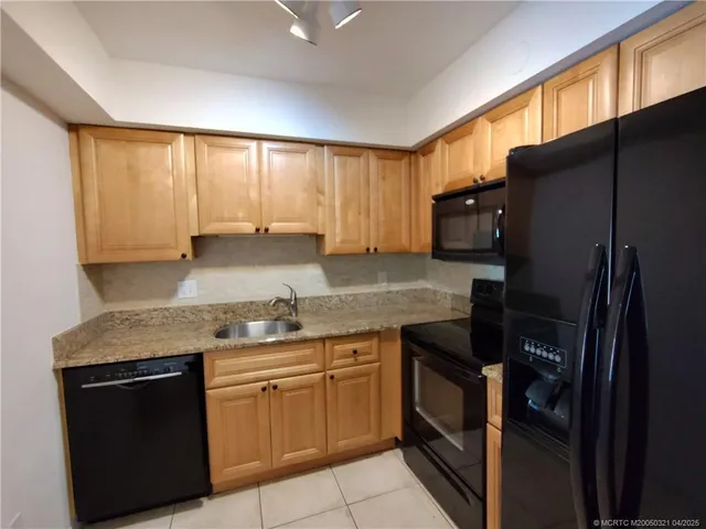 a kitchen with stainless steel appliances granite countertop a stove a sink and a refrigerator