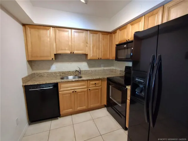 a kitchen with granite countertop a refrigerator stove and sink