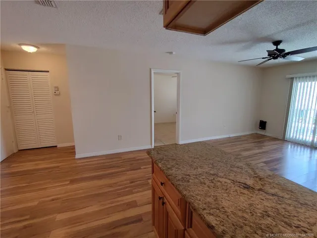 an empty room with wooden floor cabinet and windows