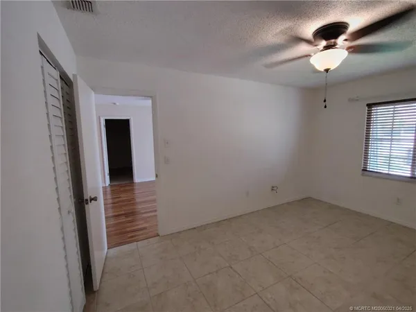 en empty room with windows and chandelier fan