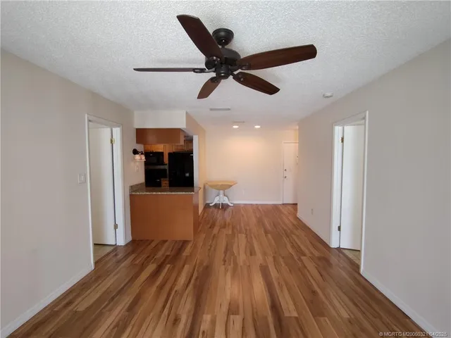 a view of empty room with wooden floor and ceiling fan