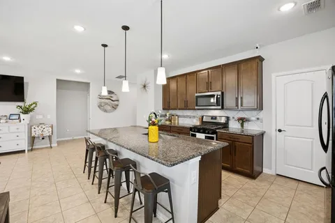 a kitchen with granite countertop a stove a sink a counter space and cabinets