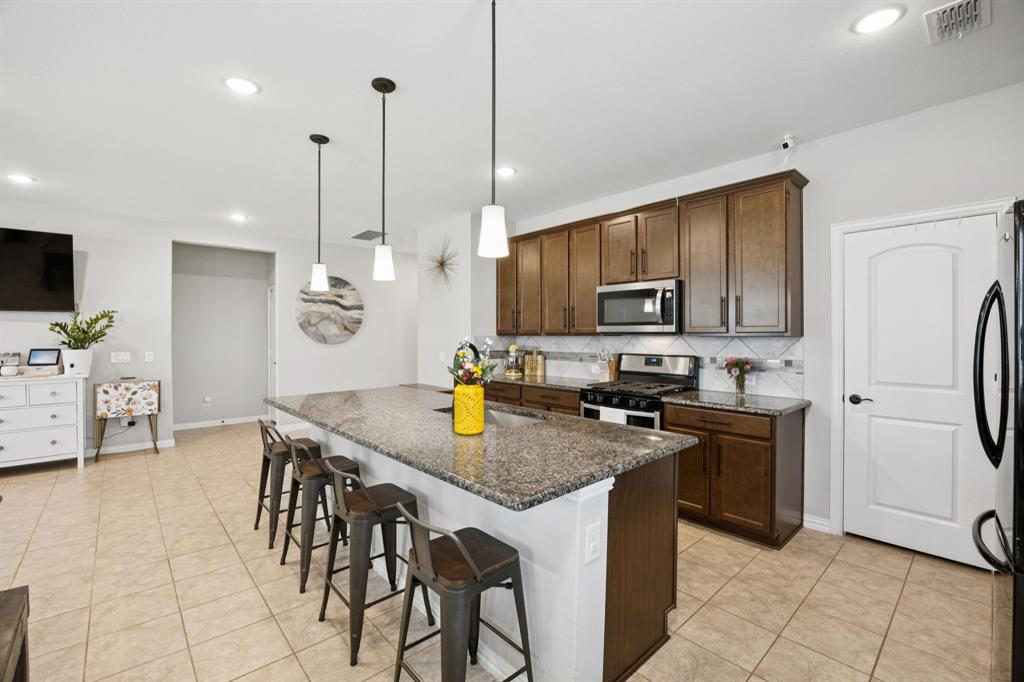 a kitchen with granite countertop a stove a sink a counter space and cabinets