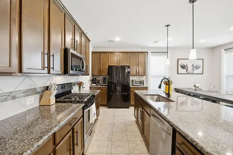 a kitchen with stainless steel appliances granite countertop a sink a stove and a wooden floors