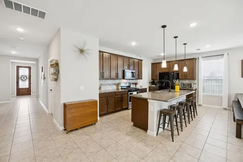 a kitchen with stainless steel appliances granite countertop a stove top oven a refrigerator and a view of living room