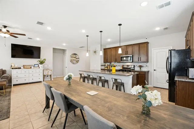 a open kitchen with stainless steel appliances granite countertop a stove a refrigerator a kitchen island a sink dishwasher a dining table and chairs with wooden floor