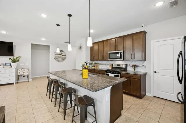 a kitchen with granite countertop a stove a sink a counter space and cabinets