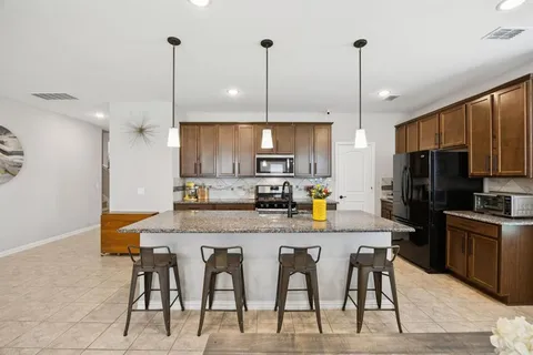 a kitchen with stainless steel appliances granite countertop a kitchen island a stove a dining table chairs and white cabinets