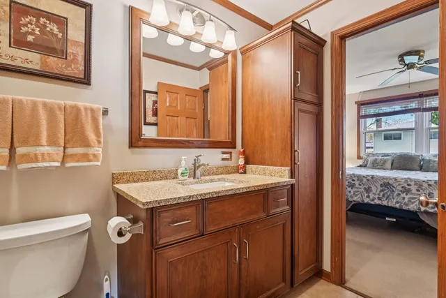 a en suite bathroom with a granite countertop sink a toilet a mirror and shower