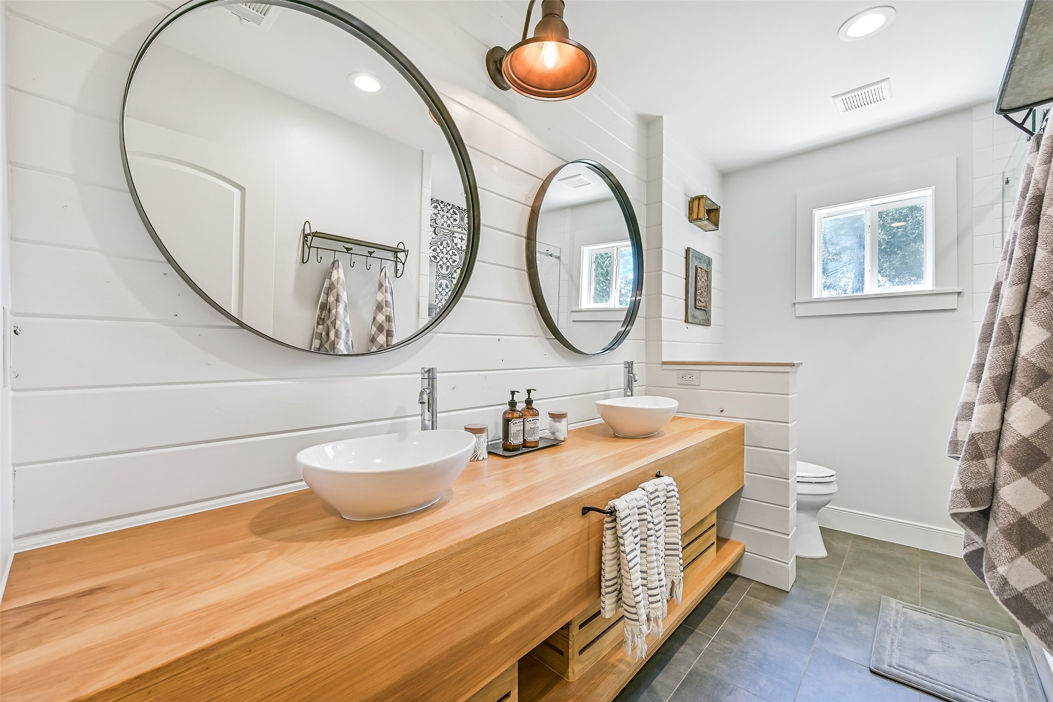 3042 Poskey Road Anahuac, TX 77514 - Photo 23 of 50 Here's a refined version of the description:
"Experience elegance in this modern bathroom with a sleek double vanity and vessel sinks, framed by chic round mirrors. Bright shiplap walls and abundant natural light create a fresh, airy feel, enhanced by contemporary fixtures.
