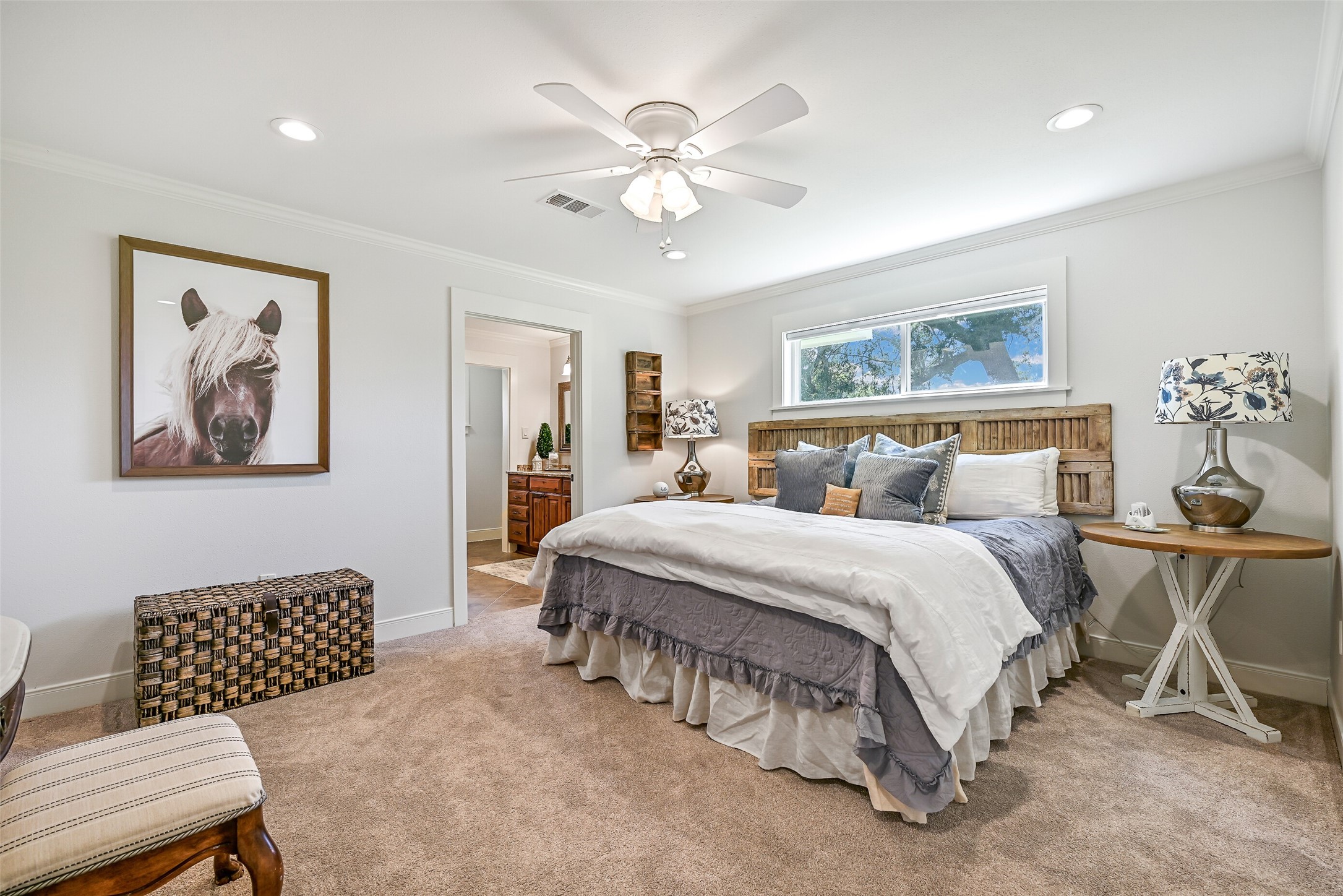 3042 Poskey Road Anahuac, TX 77514 - Photo 25 of 50 Discover a cozy bedroom with plush carpeting and abundant natural light. Featuring a large bed with an elegant headboard, stylish side tables, and unique artwork, it offers a spacious layout seamlessly connected to a bathroom.