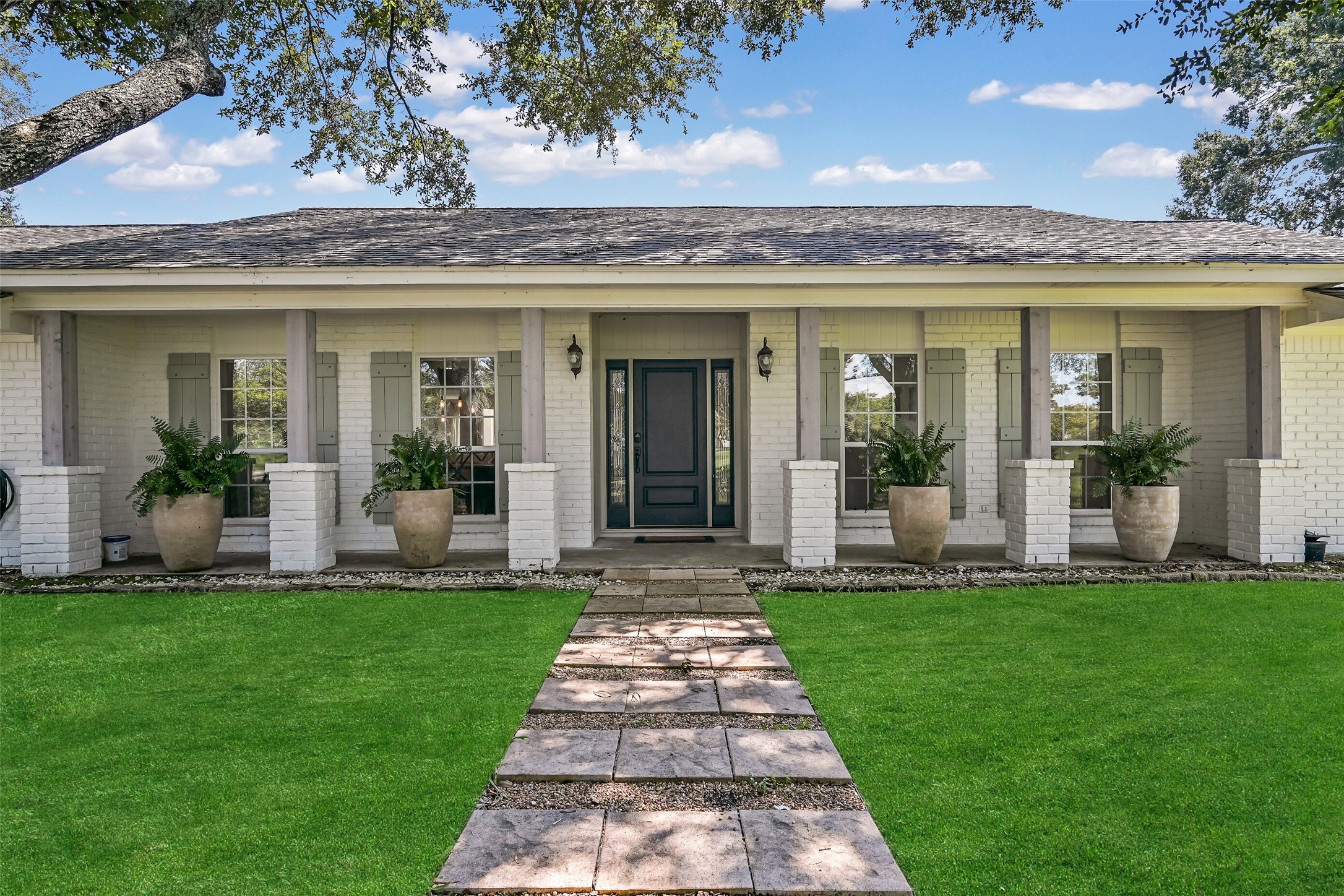 3042 Poskey Road Anahuac, TX 77514 - Photo 3 of 50 Discover tranquility in this charming single-story home, featuring a classic white brick exterior, inviting front porch, and lush lawn. Perfect for those seeking warmth and elegance.