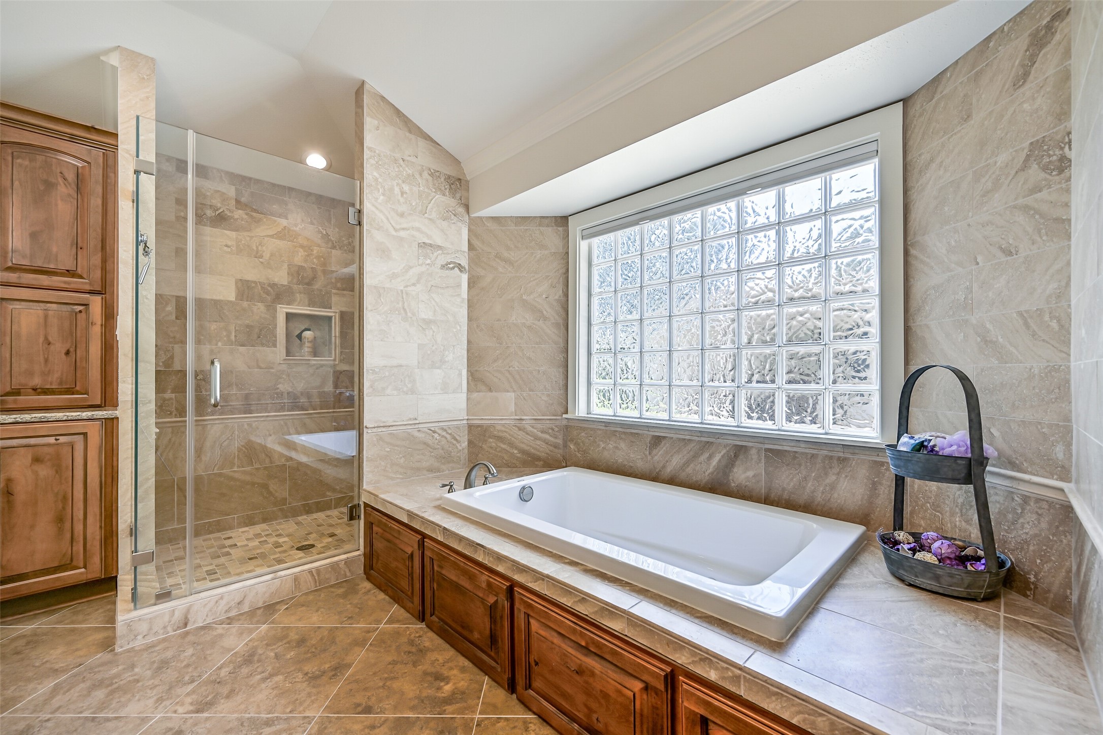 3042 Poskey Road Anahuac, TX 77514 - Photo 36 of 50 This luxurious bathroom boasts a spacious tiled shower, a soaking tub under a frosted glass window, and elegant wood cabinetry for a serene retreat.