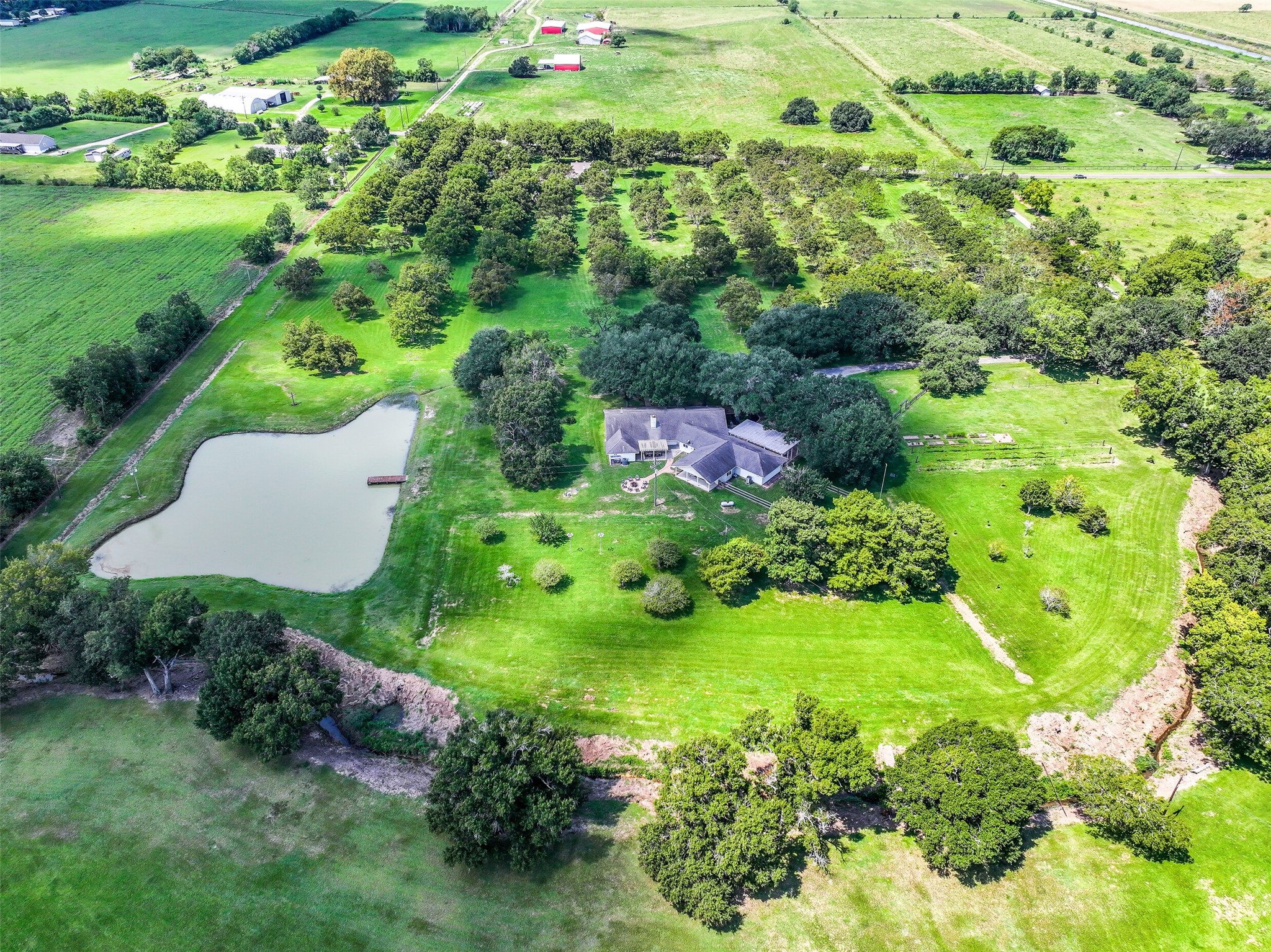 3042 Poskey Road Anahuac, TX 77514 - Photo 6 of 50 Experience serene rural living on this expansive property featuring a spacious home, surrounded by lush greenery and mature trees. Enjoy privacy, scenic views, and a picturesque pond with a dock, perfect for nature lovers.
