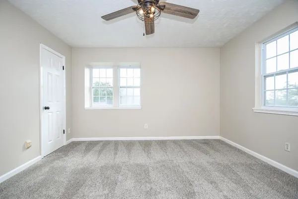 an empty room with windows and ceiling fan