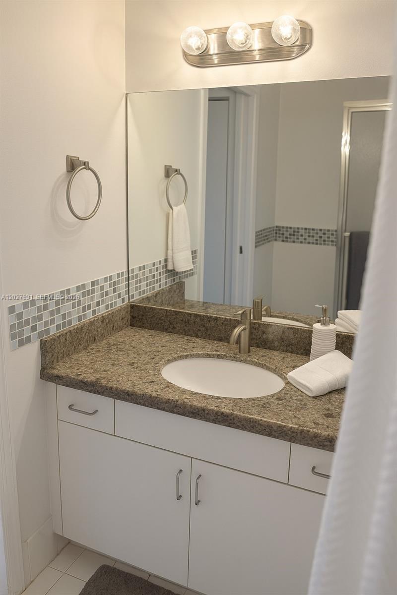 2081 Renaissance Boulevard, Unit 306 Miramar, FL 33025 - Photo 8 of 22 a bathroom with a granite countertop sink and a mirror