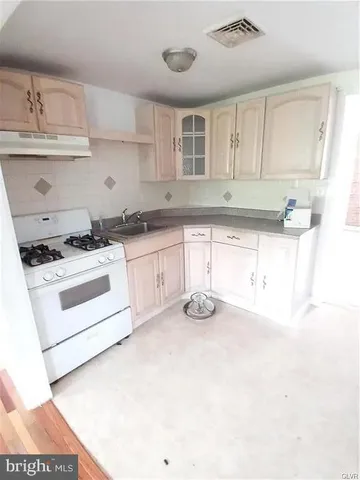 a kitchen with stainless steel appliances a stove a sink and white cabinets