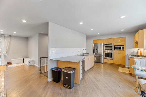 a kitchen with a table chairs refrigerator and a wooden floor