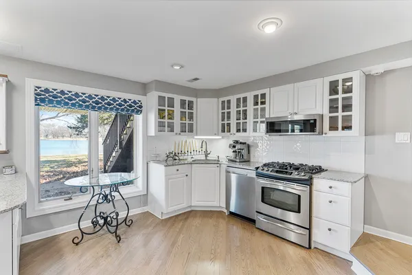 a kitchen with stainless steel appliances wooden floor and large window