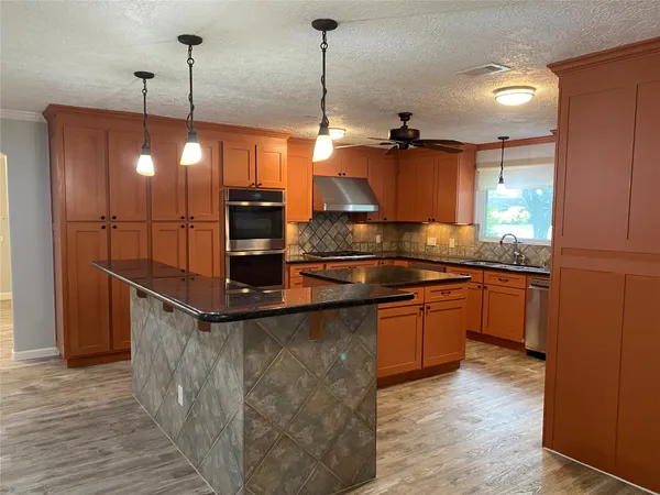 a kitchen with kitchen island a counter top space appliances and a ceiling fan