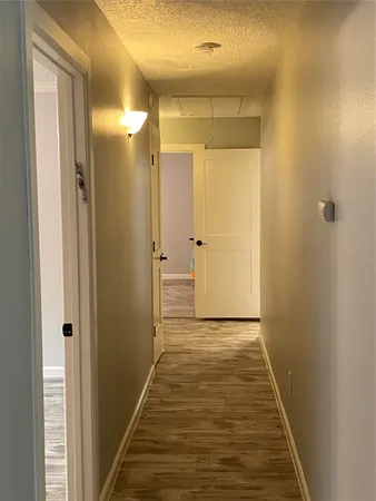 a view of a hallway with wooden floor and a bathroom