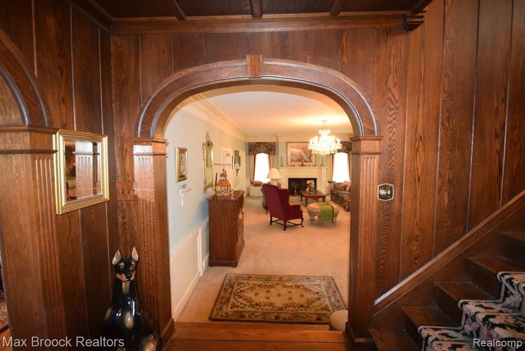 Arched entry into expansive living room with chandelier and fireplace