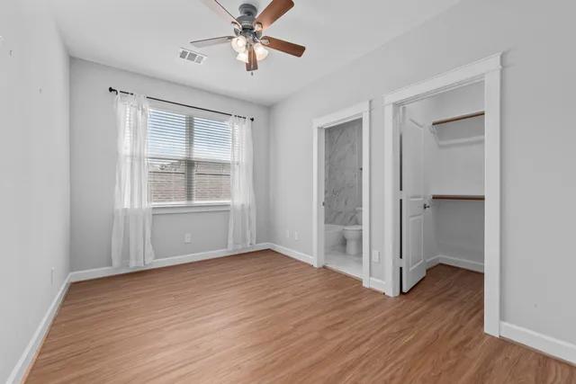 a view of empty room with wooden floor and fan