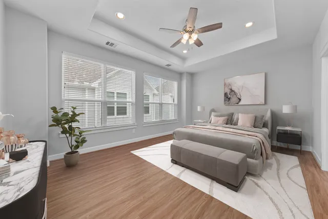 a spacious bedroom with a large bed a chandelier and windows