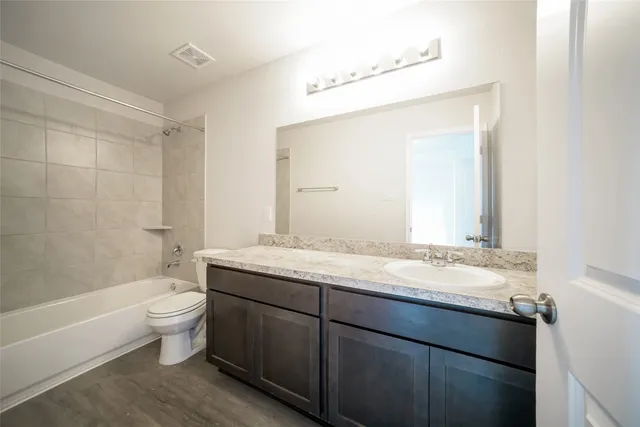 a bathroom with a granite countertop sink a toilet and a large mirror