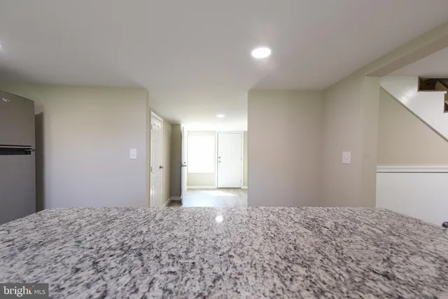 a view of a big room with a refrigerator and wooden floor