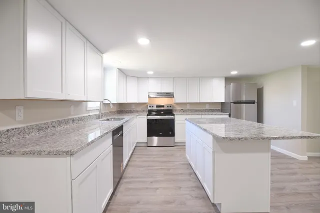 a large kitchen with granite countertop lots of counter top space and cabinets