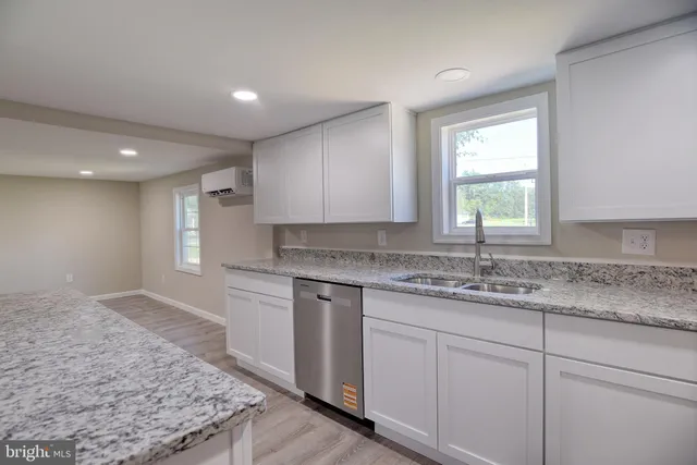 a kitchen with white cabinets granite counter tops and a window