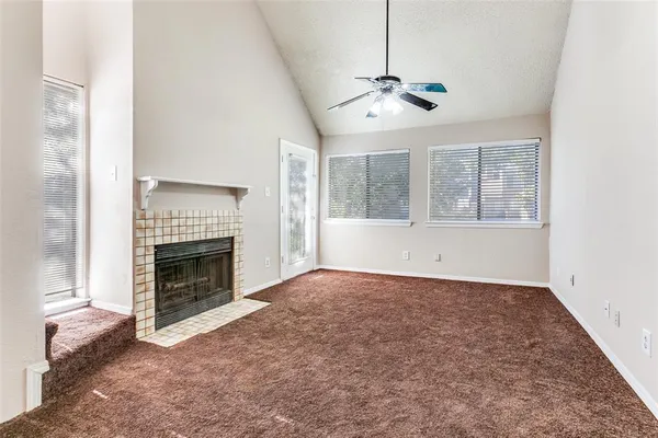 an empty room with windows fireplace and fans
