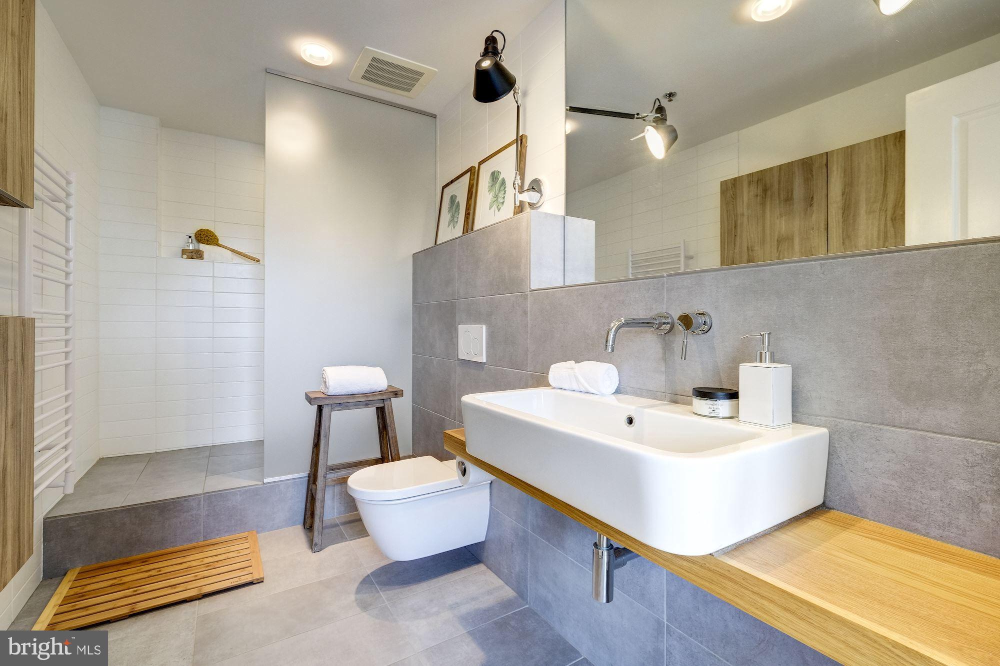 2125 14th Street Northwest, Unit 315W Washington, DC 20009 - Photo 18 of 35 a bathroom with a sink a toilet a mirror and shower