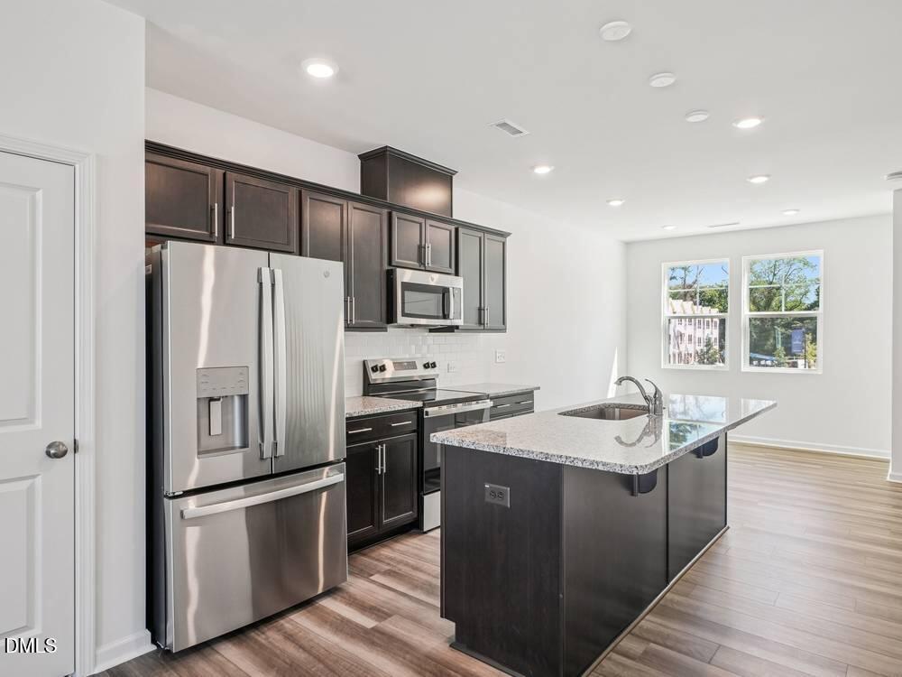 3101 White Blossom Court, Unit SAVANNAH 3103 Raleigh, NC 27610 - Photo 5 of 20 a kitchen that has a sink stainless steel appliances a refrigerator cabinets and wooden floor