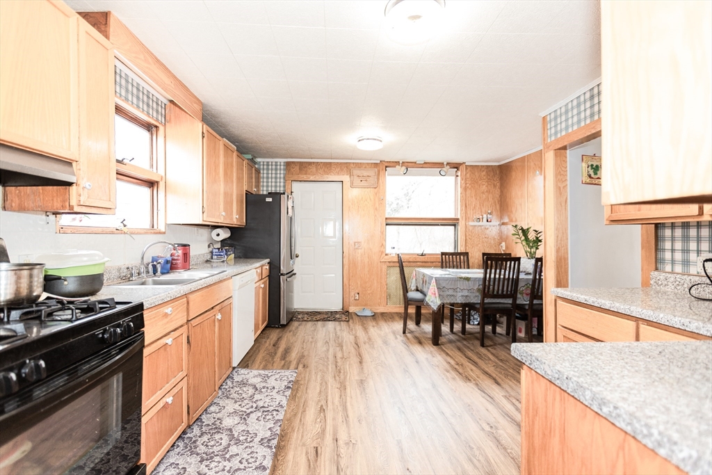 68 Spring Street Holbrook, MA 02343 - Photo 9 of 21 a kitchen with stainless steel appliances granite countertop a stove top oven a sink a dining table and chairs with wooden floor