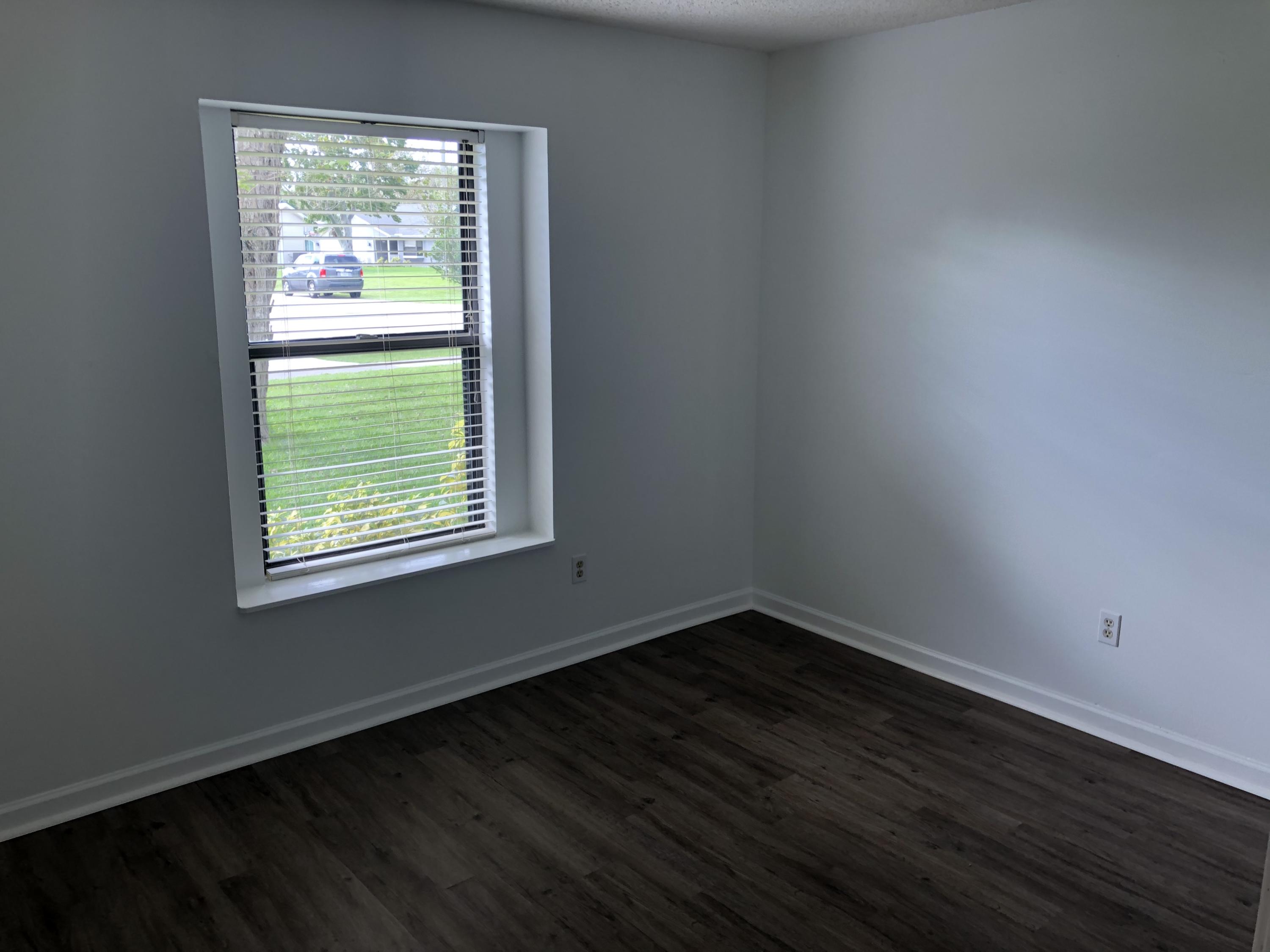 4063 Southeast Jacaranda Street Stuart, FL 34997 - Photo 12 of 15 a view of an empty room with wooden floor and a window