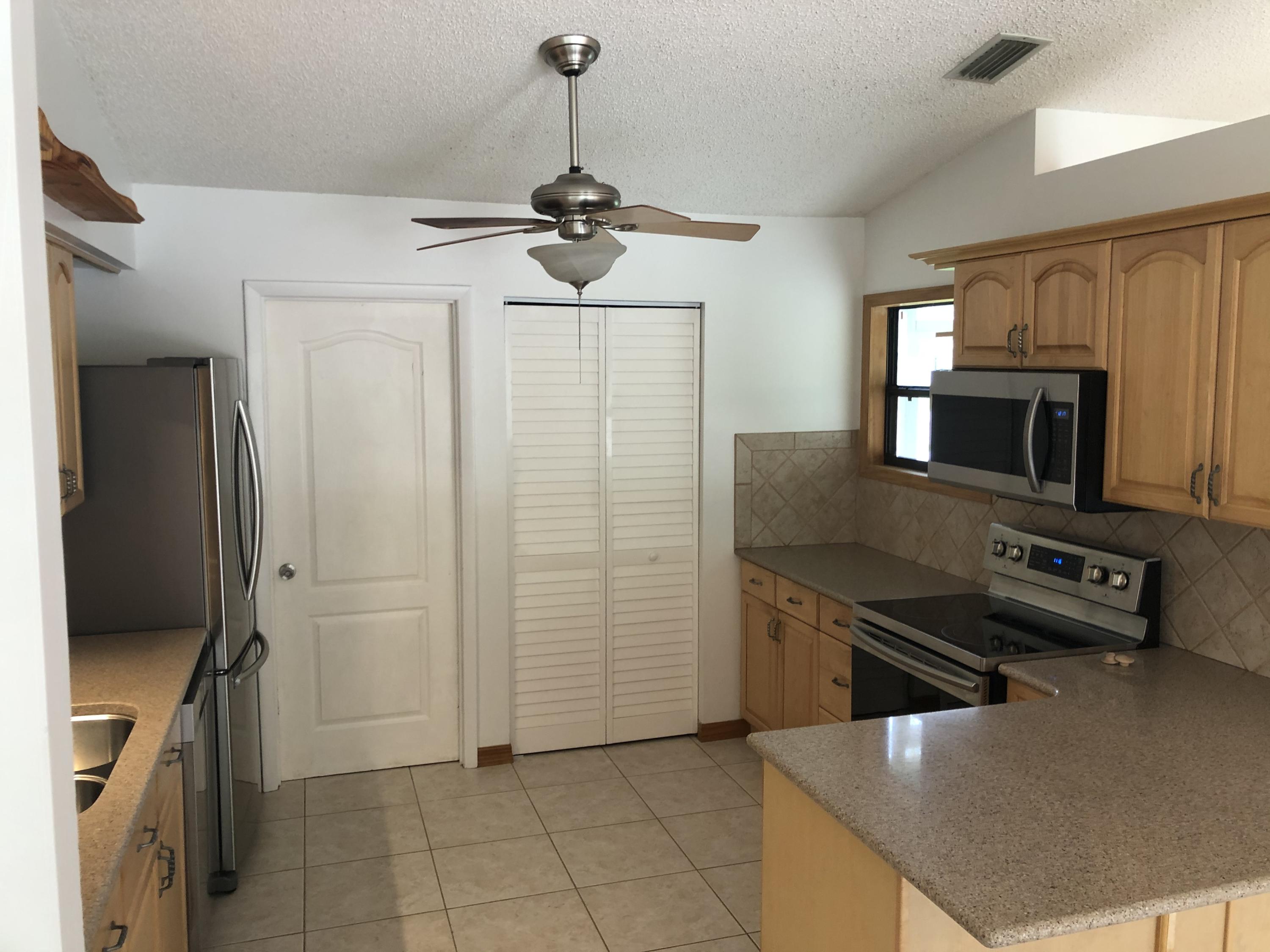 4063 Southeast Jacaranda Street Stuart, FL 34997 - Photo 4 of 15 a kitchen with stainless steel appliances granite countertop a refrigerator a stove and a sink