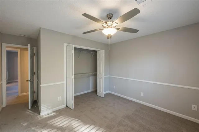 an empty room with closet and a chandelier fan