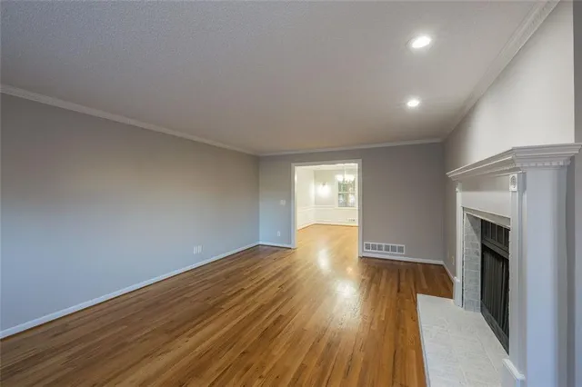 a view of empty room with wooden floor and fireplace