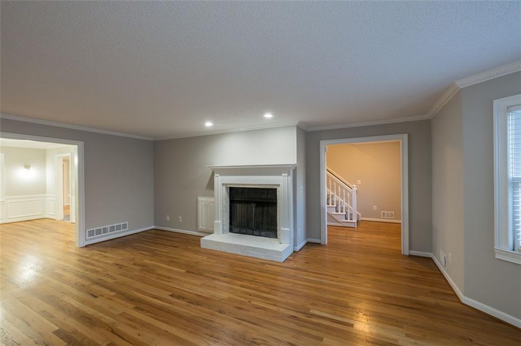 4648 Calumet Circle Northwest Duluth, GA 30096 - Photo 6 of 37 an empty room with wooden floor fireplace and windows