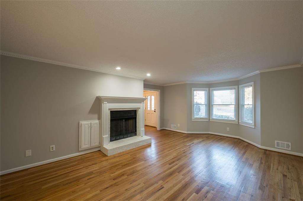 4648 Calumet Circle Northwest Duluth, GA 30096 - Photo 7 of 37 an empty room with wooden floor fireplace and windows