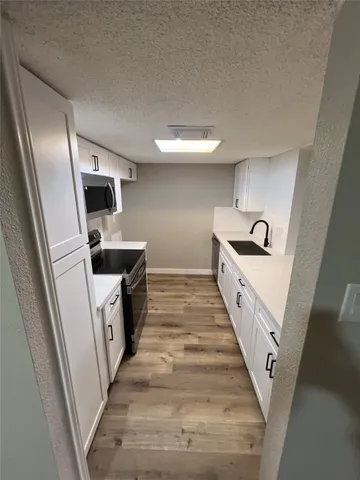 a kitchen with white cabinets and sink