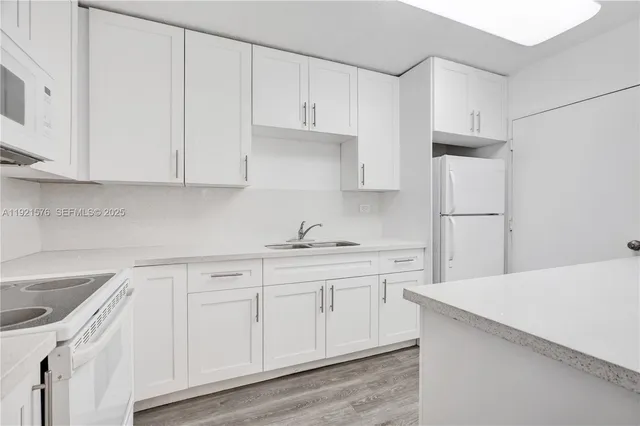 a kitchen with white cabinets and white appliances