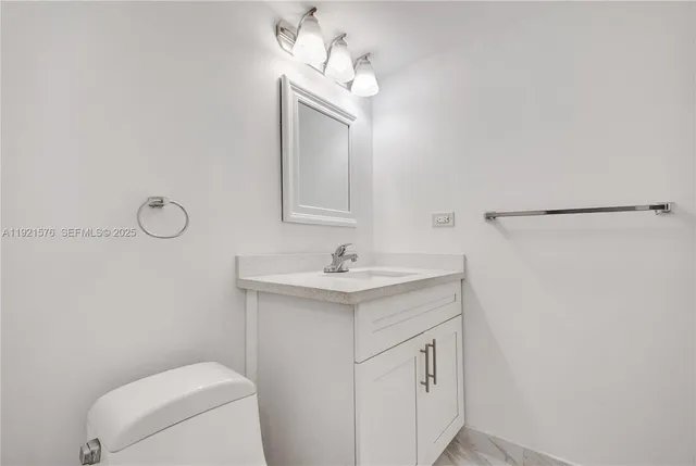 a bathroom with a granite countertop sink a toilet and a mirror
