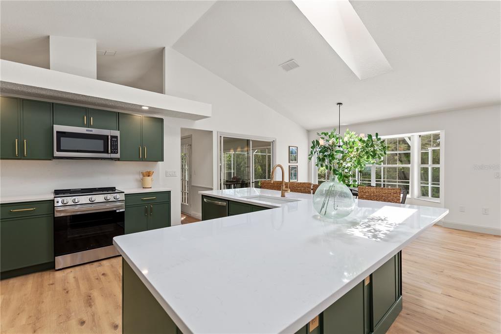 419 Silas Court Spring Hill, FL 34609 - Photo 14 of 56 a kitchen with stainless steel appliances kitchen island granite countertop a refrigerator a stove top oven a sink dishwasher and wooden floor