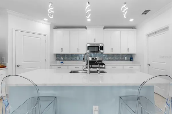 a kitchen with stainless steel appliances a stove a sink white cabinets and a refrigerator