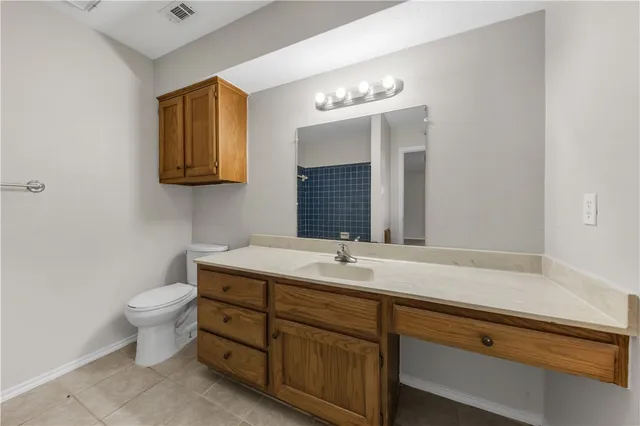 a bathroom with a granite countertop sink a toilet and mirror