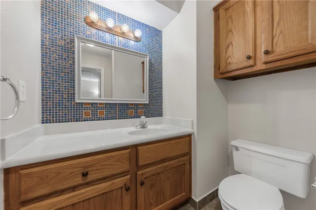 a bathroom with a granite countertop toilet sink and mirror