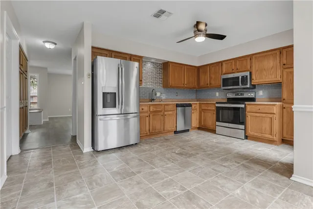 a kitchen with stainless steel appliances granite countertop a stove top oven a sink and a refrigerator